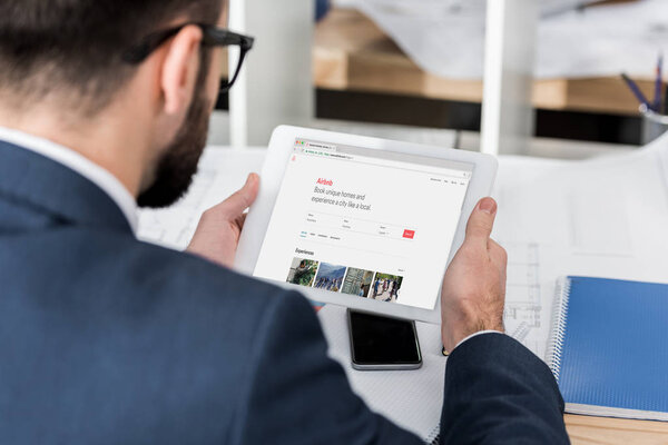 businessman holding tablet with loaded airbnb page