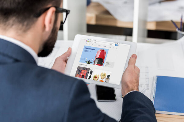 business man holding tablet with loaded ebay page
