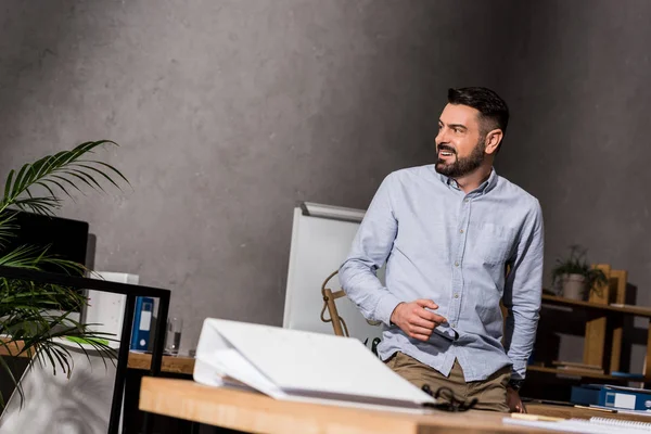 Homme Affaires Souriant Appuyé Sur Table Dans Bureau Regardant Loin — Photo gratuite