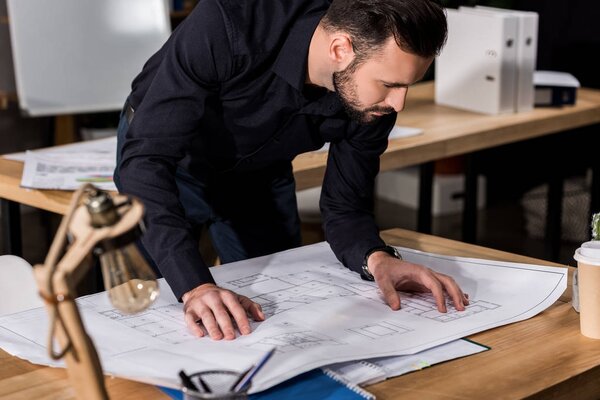 handsome architect looking at blueprints on table