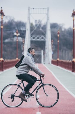 yakışıklı yetişkin adam binicilik bisiklet bulutlu gün yaya köprüsü üzerinde