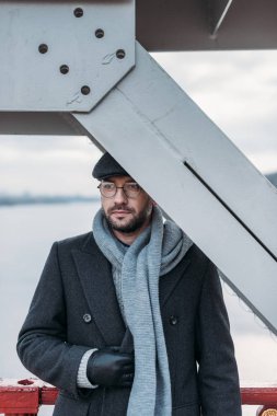 Köprüde duran ve onun inşaat ile baş kapsayan yakışıklı yetişkin adam