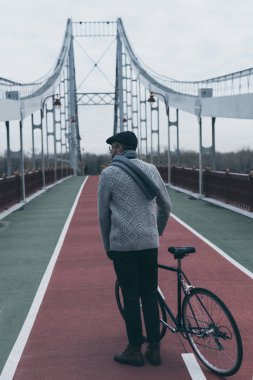 arkadan görünüşü şık Bisiklet duran adamla yaya köprüsü üzerinde
