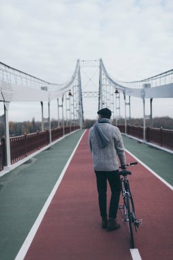 arkadan görünüşü şık Bisiklet duran adamla yaya köprüsü üzerinde