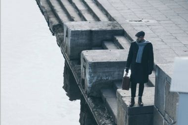 nehir kıyısında bir bavul konumu olan yetişkin adam yüksek açılı görünüş