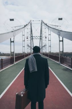 arkadan görünüşü bavul duran adamla yaya köprüsü üzerinde