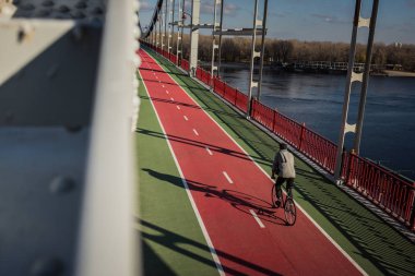 high angle view of man riding bicycle on pedestrian bridge over river clipart