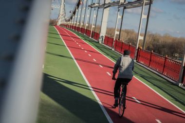 stylish man riding bicycle on pedestrian bridge with biking road clipart