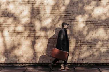yetişkin adam tuğla duvarın önünde yürüyüş çanta yan görünüm