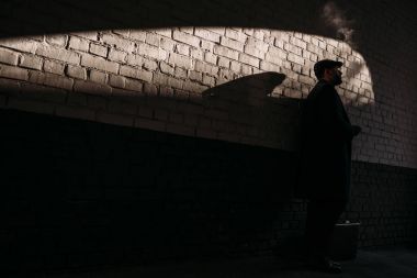 adam tuğla duvarın önünde sigara silüeti