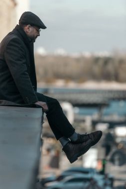 Yalnız orta yaşlı adam binanın çatısında oturmuş