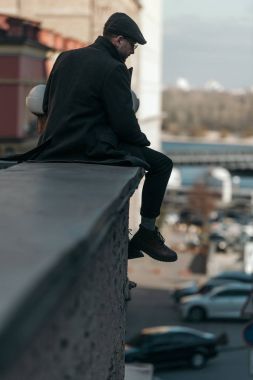 binanın çatı üzerinde oturan yakışıklı orta yaşlı adam