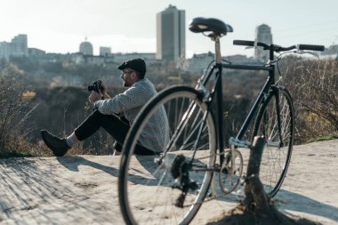yakışıklı yetişkin adam vintage film kamerası ve kırsal yolda oturup bisiklet