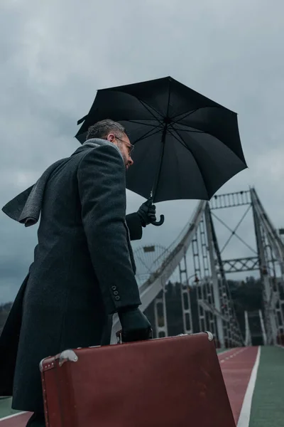 우산과 수하물 보행자 다리를 지나가는 남자의 — 스톡 사진