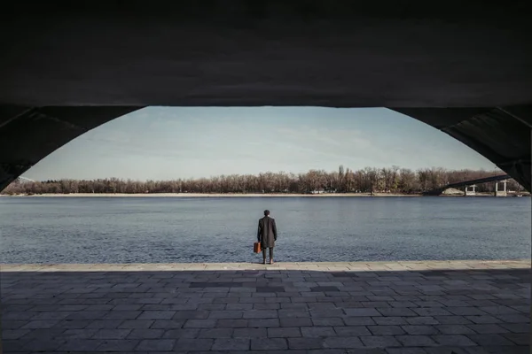 Schöner Erwachsener Mann Mit Koffer Steht Ufer Des Flusses — kostenloses Stockfoto