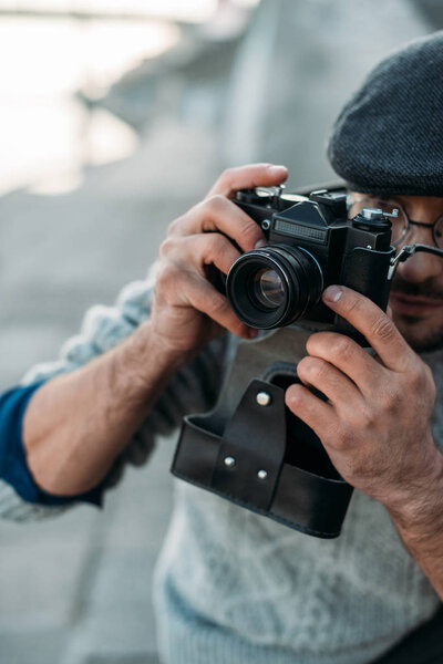 close-up shot of handsome adult man with vintage film camera outdoors