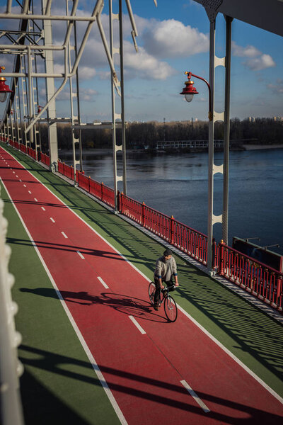 high angle view of adult man riding bicycle on pedestrian bridge over river