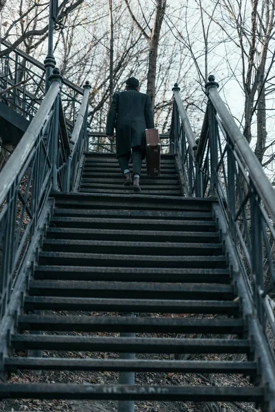 stock image back view of man with suitcase going upstairs