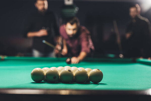 handsome man playing in pool at bar with friends