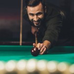 Front view of handsome man playing russian pool at bar