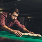 Handsome man forming triangle of russian pool balls at bar
