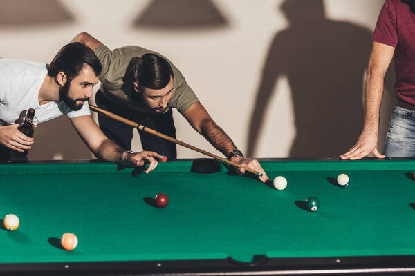 company of handsome men playing in pool  