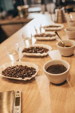 close up view of arranged bowls with coffee beans and grind coffee for food function on wooden tabletop clipart