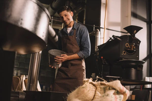 コーヒー ショップでの作業の手で金属製のバケツで若いコーヒー豆を炒る — ストック写真