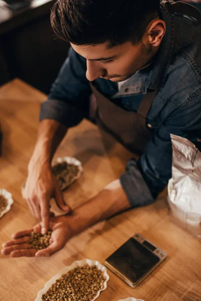 木製のテーブルでコーヒー豆の品質をチェックする人の選択と集中 — ストック写真