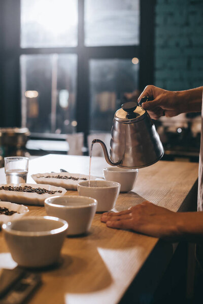 selective focus of man pouring hot water into bowl with grind coffee