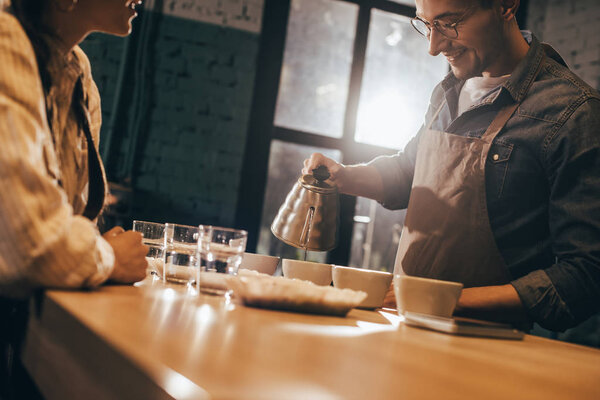 selective focus of smiling man pouring hot water into bowl with grind coffee