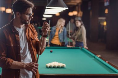 genç adam tebeşirlenme cue Bilardo masasına yanında bar arkadaş grubu 