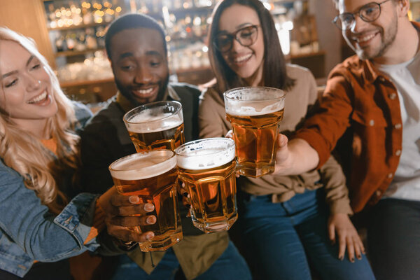 cheerful multiculture friends drinking beer together at bar
