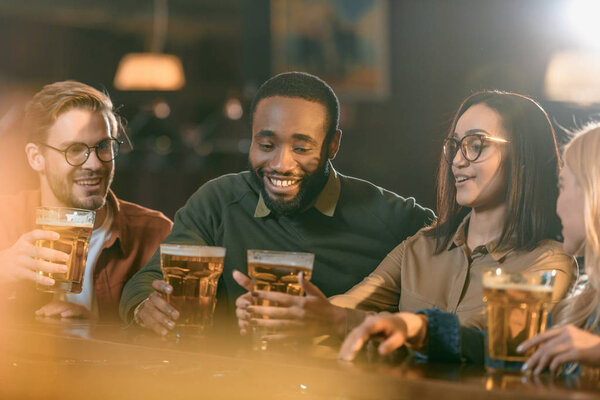 счастливые мультикультурные друзья, проводящие время в баре
