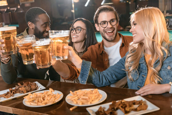 молодая мультикультурная компания ест и пьет в баре
