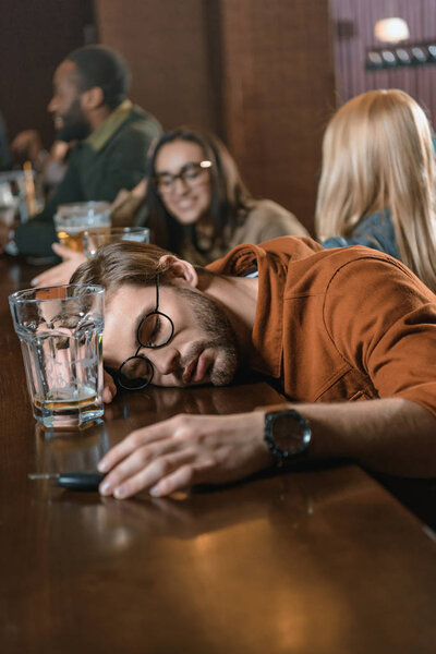 very drunk caucasian man with automobile keys at bar with friends