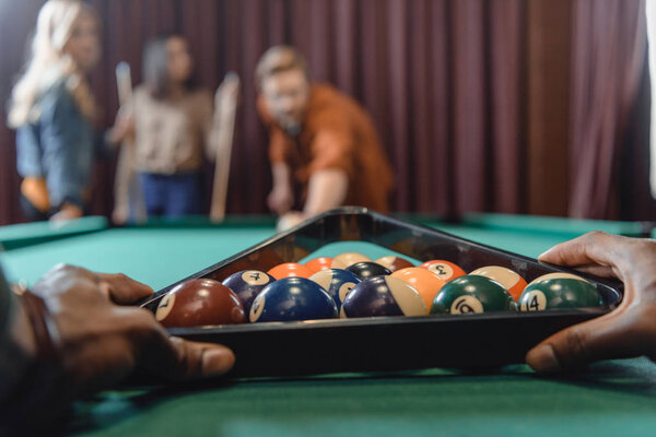 cropped image of male hands forming set of billiard balls by triangle