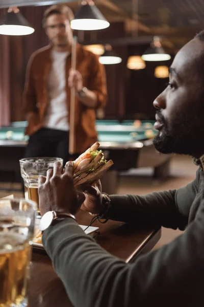 Αφρικανική Amercian Άνθρωπος Τρώει Σάντουιτς Στο Μπαρ — Δωρεάν Φωτογραφία