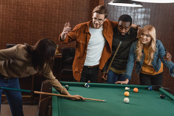 young attractive multiethnic friends playing in pool at bar