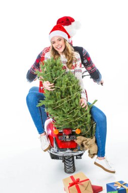 Noel ağacı binme scooter ile çift gülümsüyor, uzanarak, üzerinde beyaz izole hediyeler dağılmış