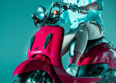 Kısmi görünümü şık giyim kırmızı scooter üzerinde oturan adamın