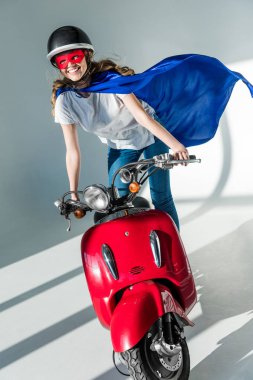mutlu kadın süper kahraman kostümü ve kırmızı scooter üzerinde koruyucu kask