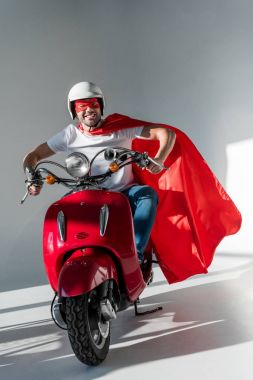 koruyucu kask, süper kahraman maske ve kırmızı scooter sürme cape gülümseyen adam