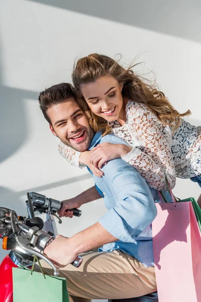 快乐的年轻夫妇与购物袋骑机车 — 图库照片