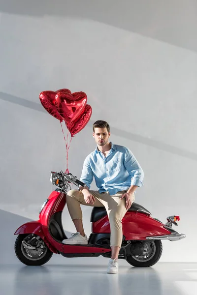 Giovane Uomo Con Palloncini Forma Cuore Seduto Scooter Rosso — Foto Stock