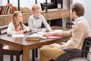 Baba evde eğitim ile çocuklara yardım tekerlekli sandalye üzerinde