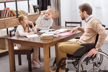 Baba evde eğitim ile çocuklara yardım tekerlekli sandalye üzerinde