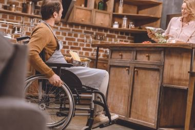 evde birlikte yemek tekerlekli sandalyede engelli erkekle kadının seçici odak  