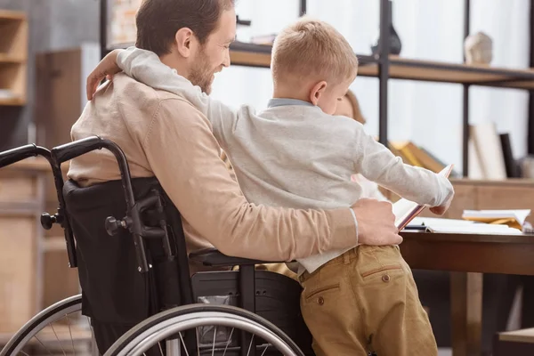 Father Wheelchair Teaching Kids Home Hugging Son — Stock Photo, Image