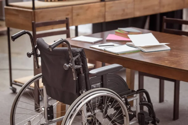 Silla Ruedas Vacía Cerca Mesa Con Cuadernos — Foto de Stock